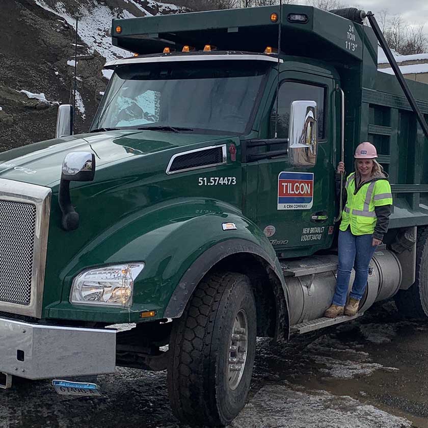 person wearing pink hard hat standing next to truck