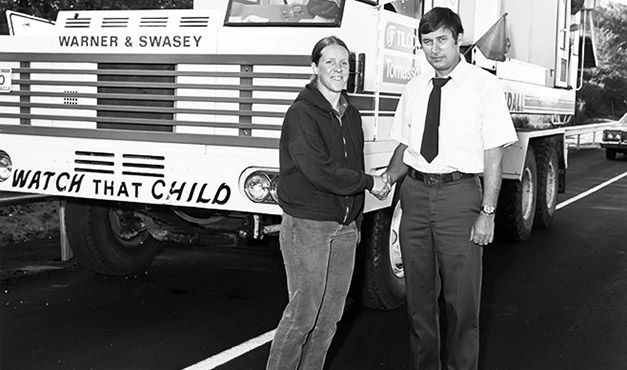 two people shaking hands in front of truck