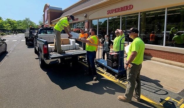 employees in safety gear unloading truck outside of store